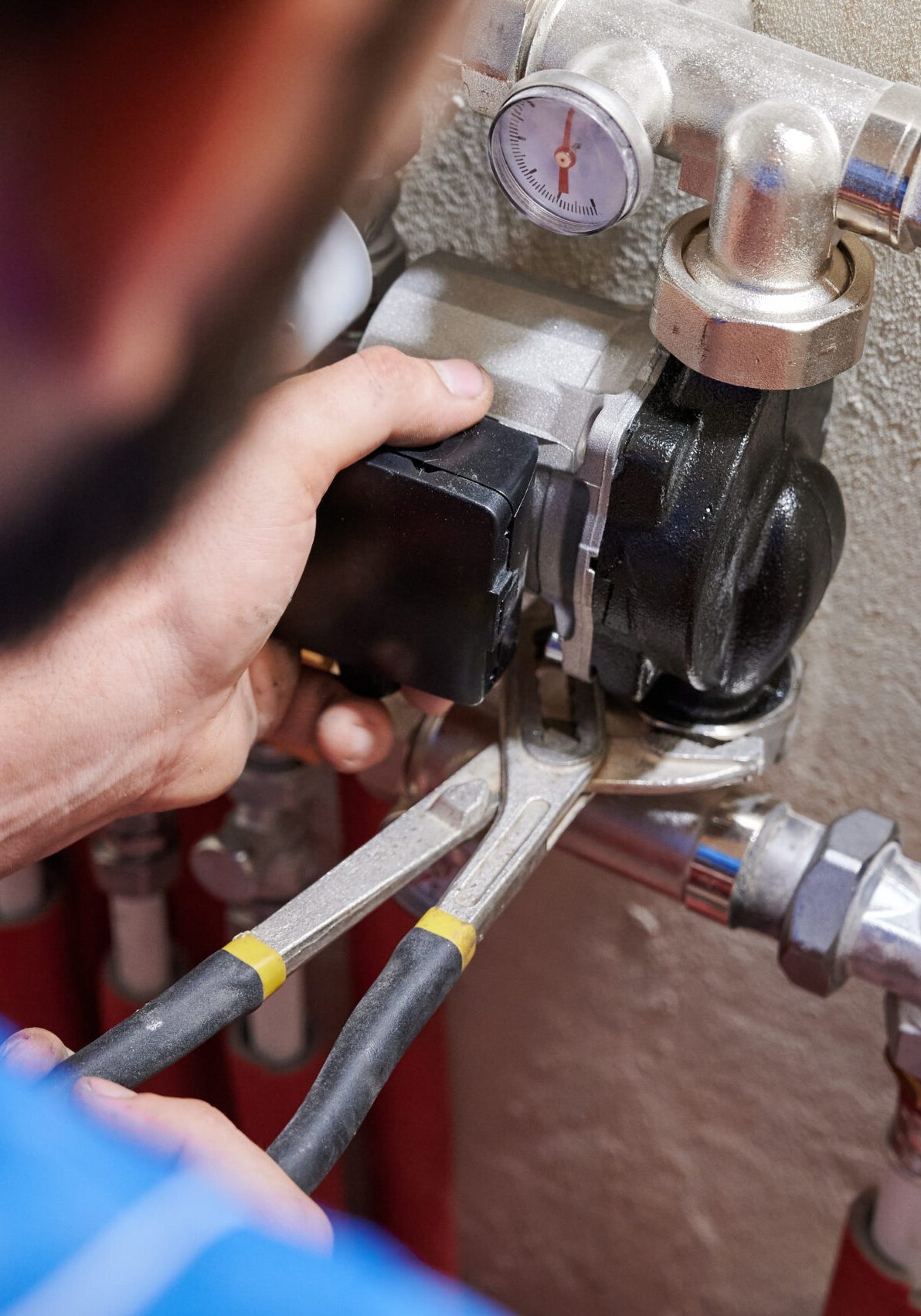 Close up of worker hands using wrenches, installing water pump in apartment. Man plumber working on heating system installation. Concept of radiator installation, plumbing works and home renovation.