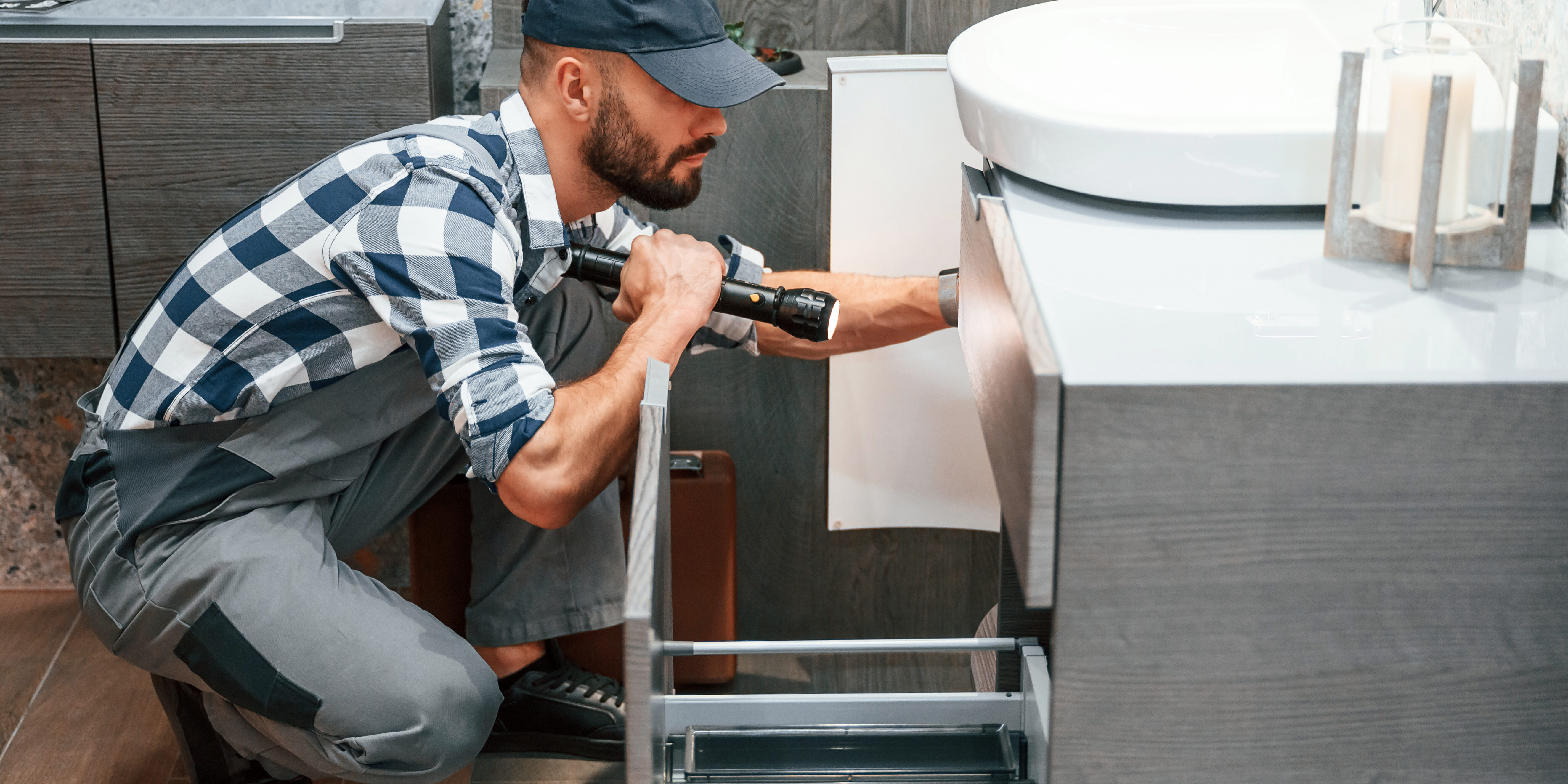 Plumber in uniform is working indoors Plumber in uniform is working indoors